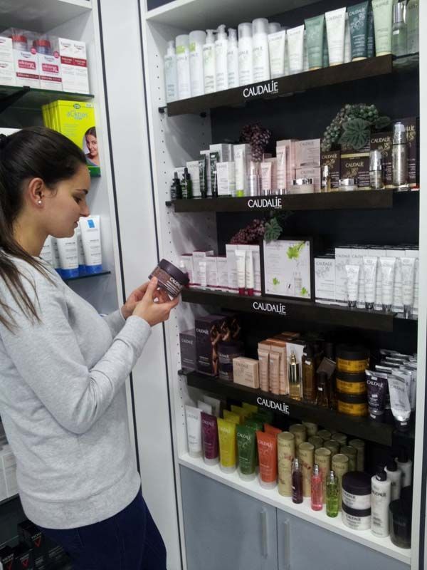 Una mujer está mirando una botella de loción en una farmacia.