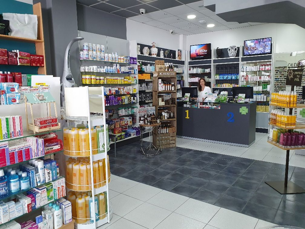 Una mujer está de pie ante un mostrador en una farmacia.