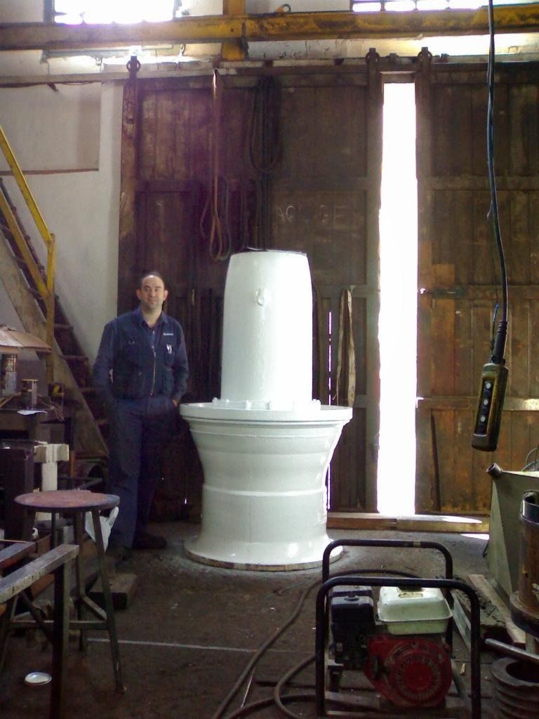 Una persona de pie junto a una gran máquina industrial blanca en un taller
