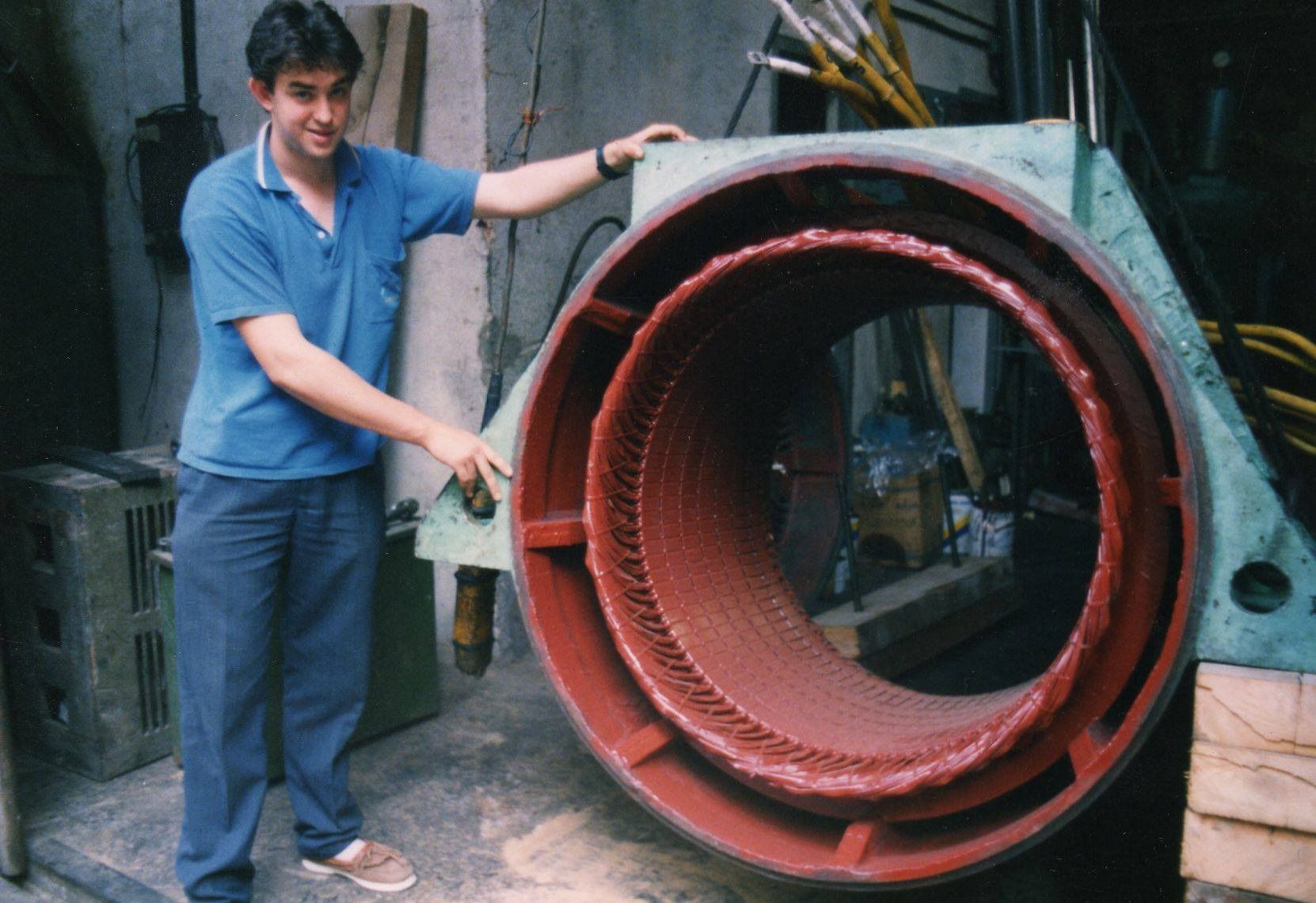 Hombre de pie junto a una gran tubería industrial roja o a una sección de túnel al aire libre
