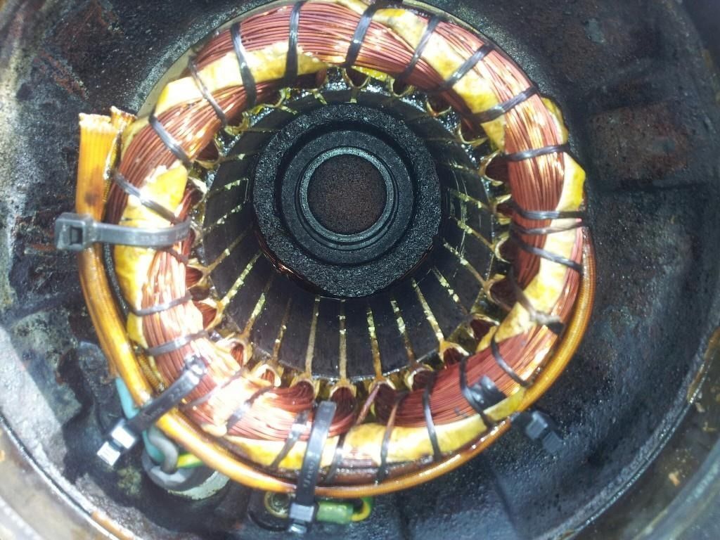 Primer plano del estator de un motor eléctrico circular con bobinados de cobre y un cubo central oscuro.