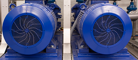 Dos grandes ventiladores industriales azules, uno al lado del otro, en una fábrica