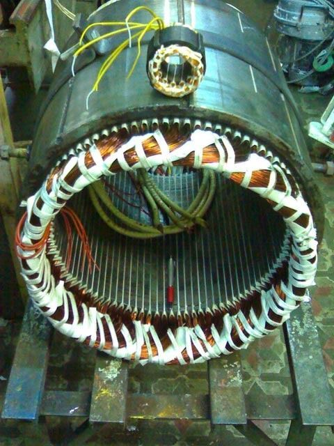 Motor eléctrico industrial grande con devanados de cobre y cableado expuestos en el suelo de una fábrica