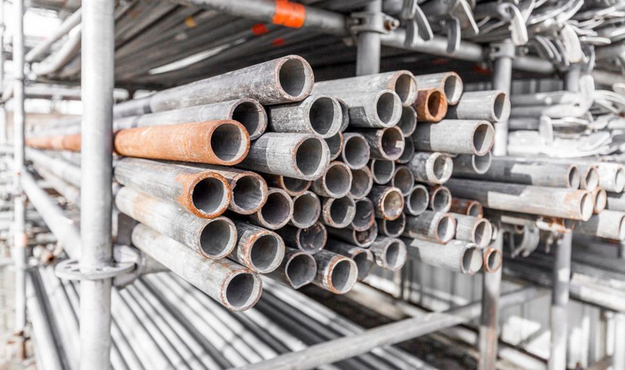 In einem Freiluftlager sind Rohre auf einem Gerüst gestapelt.