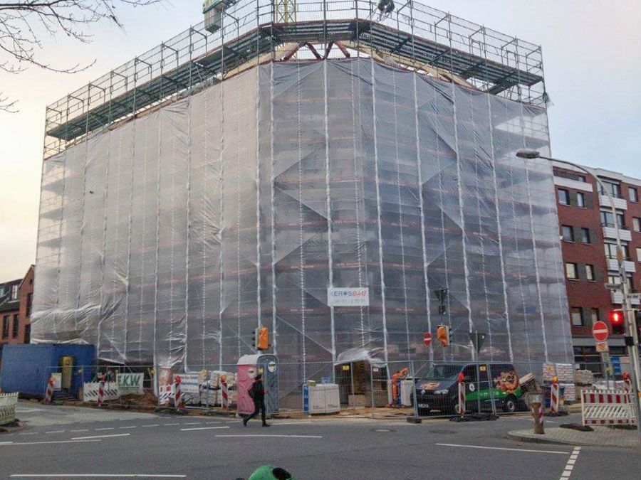 Ein mit Gerüsten und Schutzplanen verhülltes Gebäude an einer Straßenecke in der Stadt, die sich im Bau befindet.