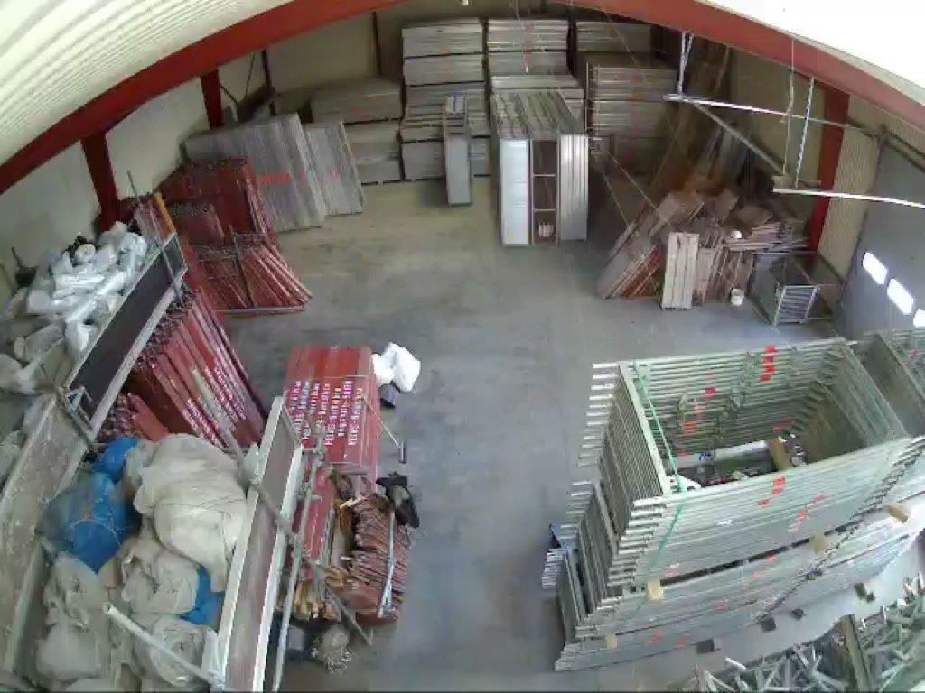 Innenansicht einer Lagerhalle mit verschiedenen Stapeln von Metallgerüsten und Baumaterialien.