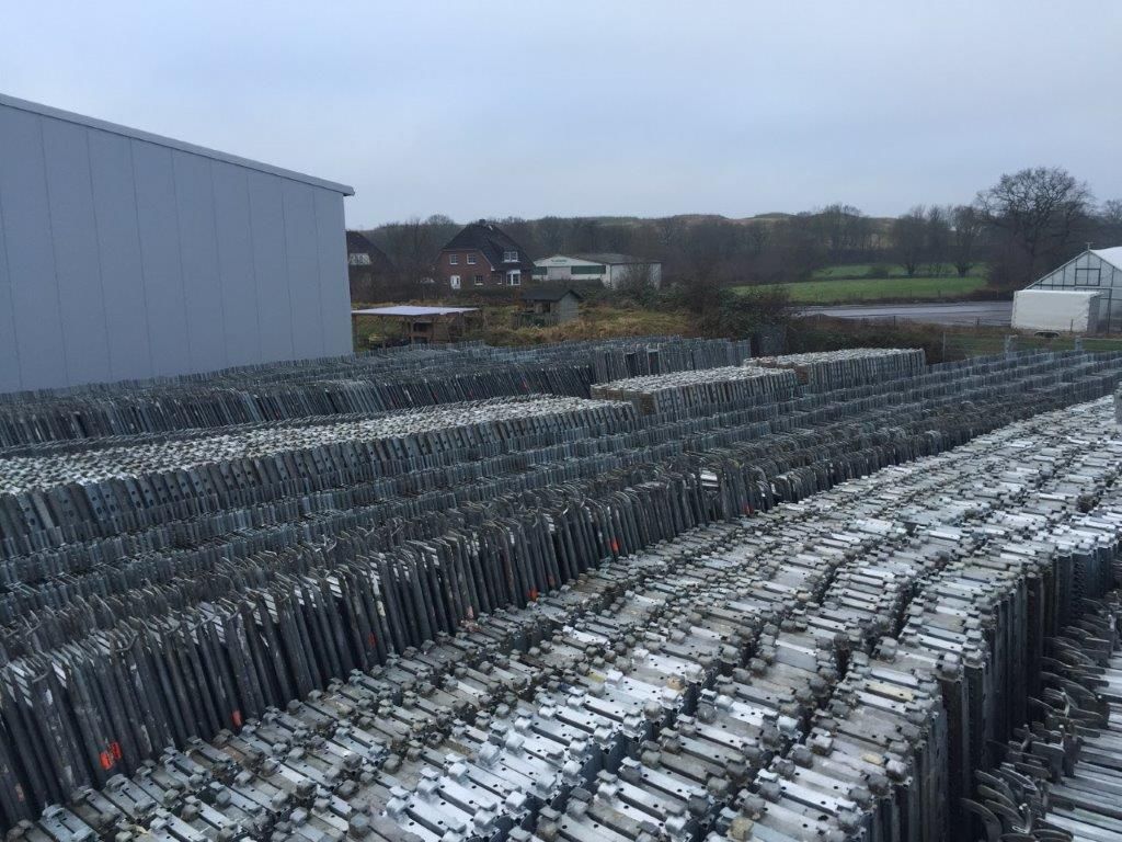 Metallgerüste stapeln sich vor einem Gebäude an einem bewölkten Tag.