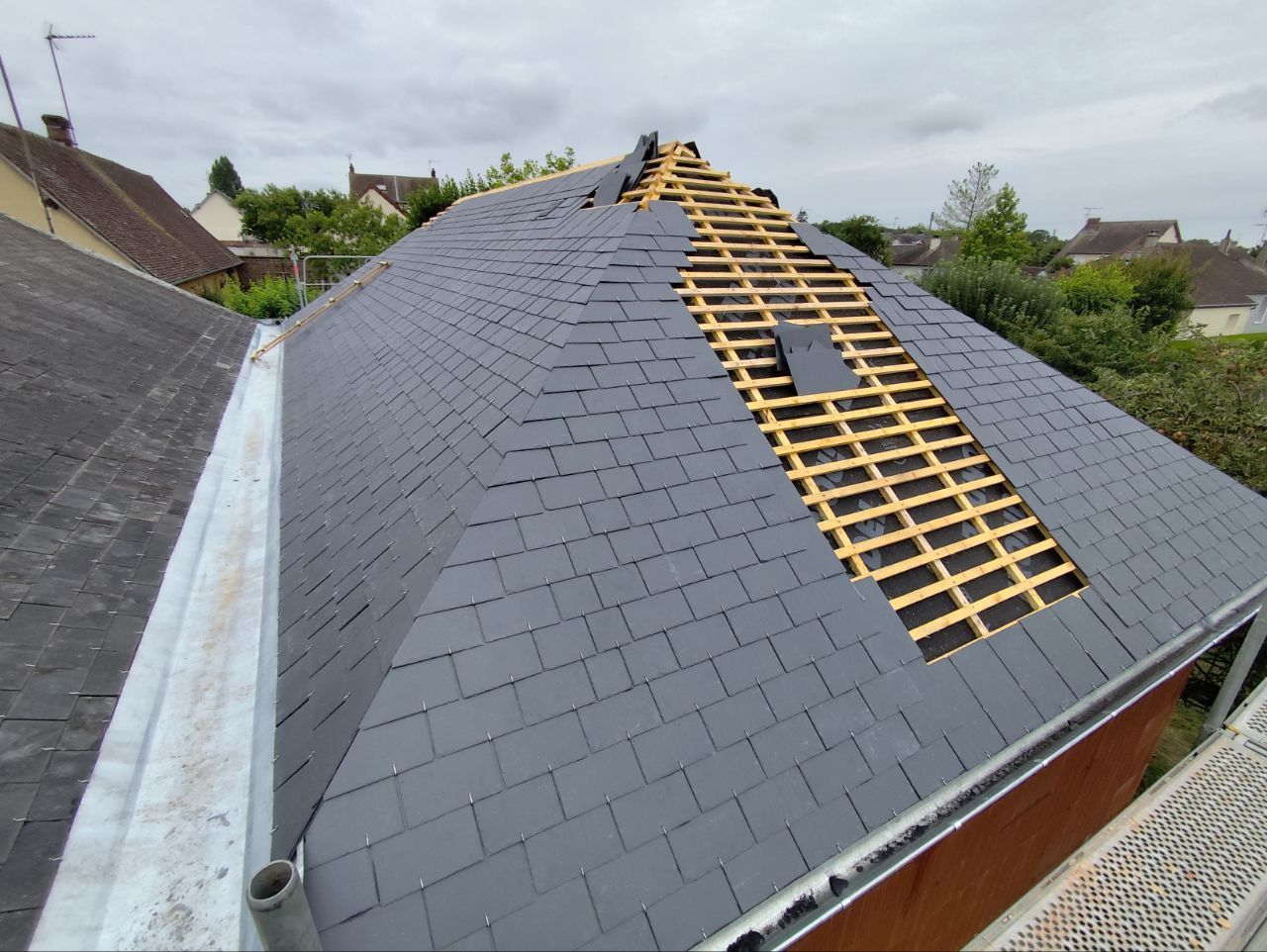 Toit de tuiles orange sur un ciel bleu éclatant parsemé de nuages ​​blancs.