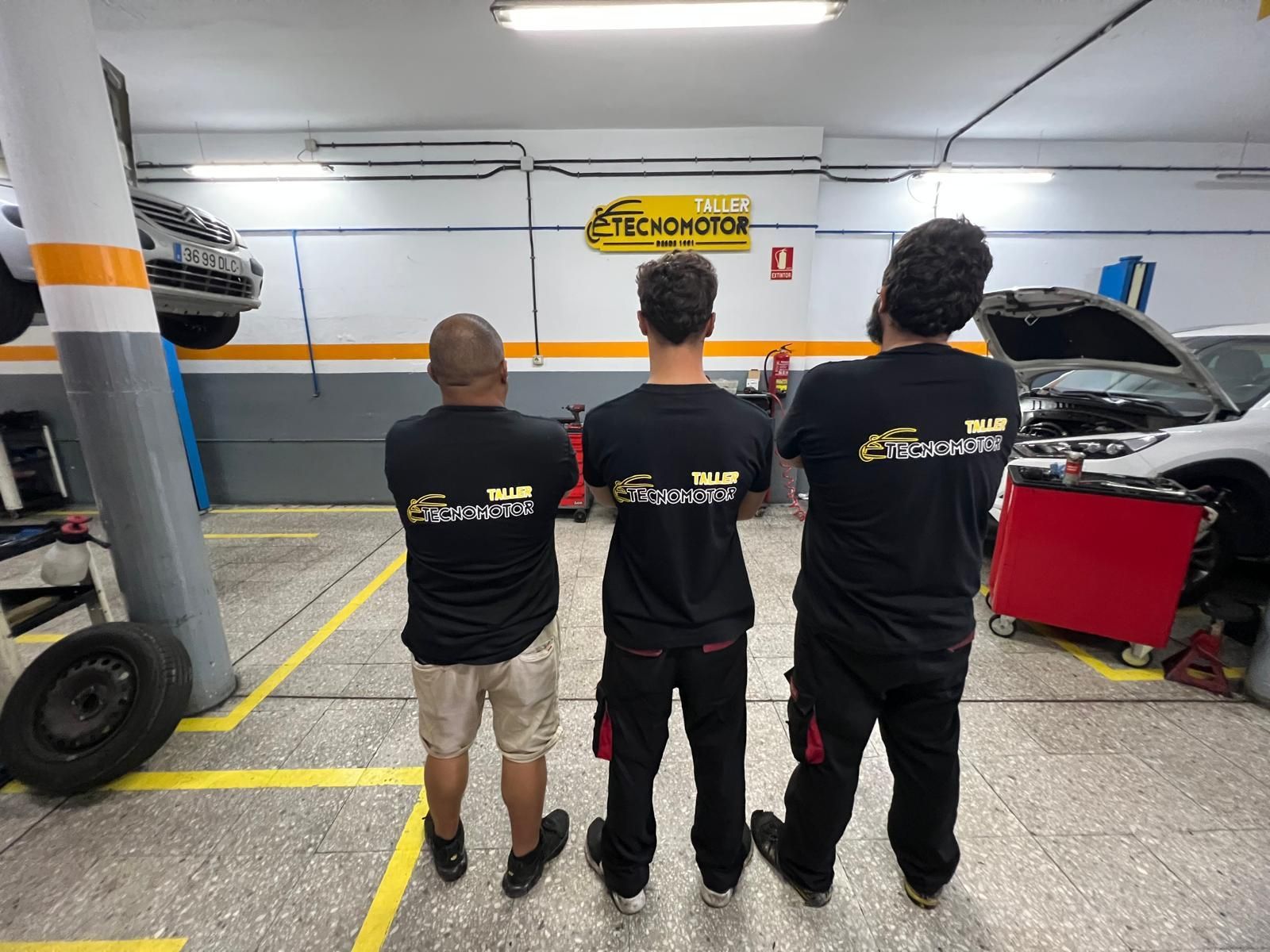 Tres mecánicos con camisetas negras con el logo