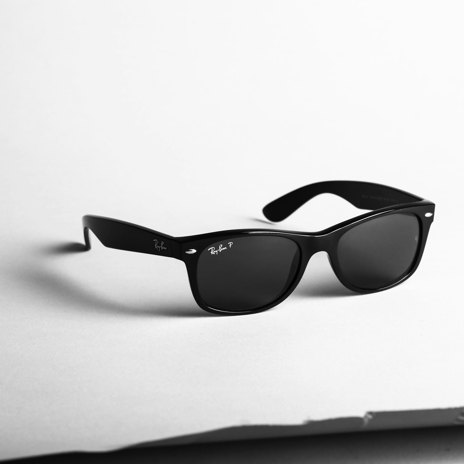 Lunettes de soleil noires à monture brillante sur fond blanc