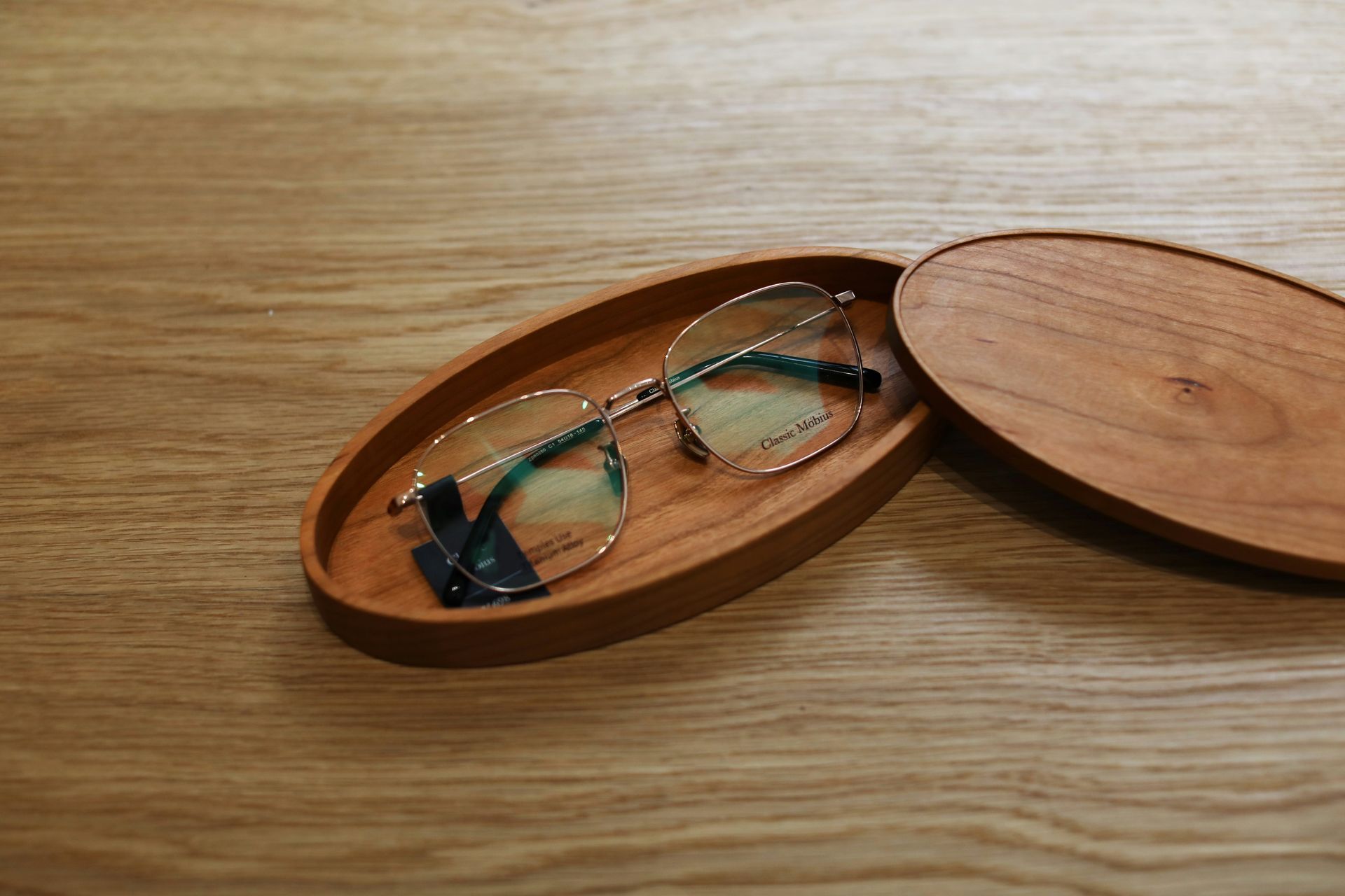 Des lunettes dans un étui en bois ouvert, posé sur une table en bois
