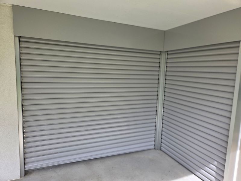 Coin vide d'un débarras avec volets roulants métalliques gris fermés et sol en béton