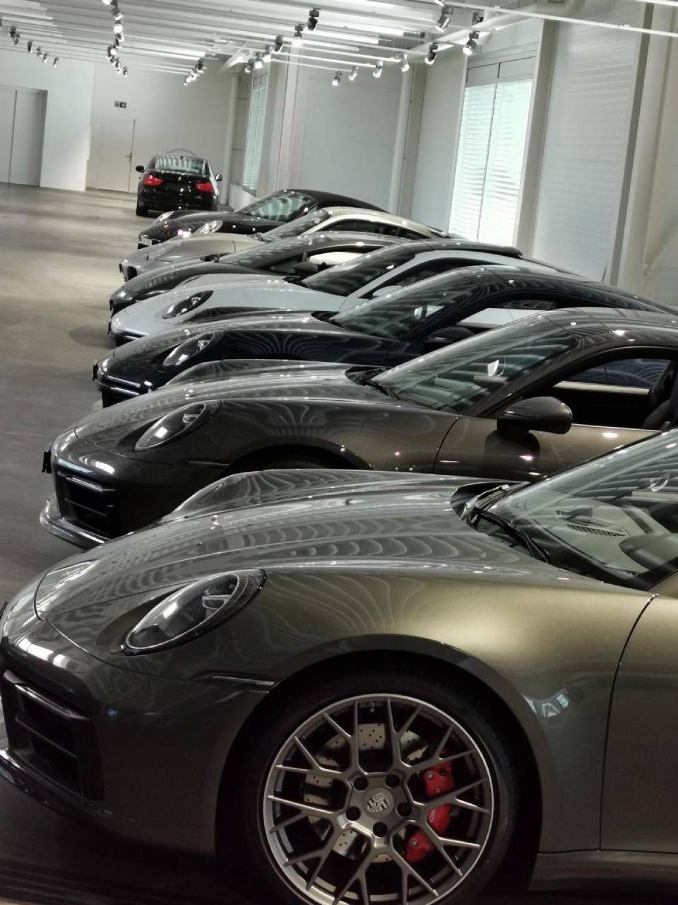 In einem Ausstellungsraum parken mehrere Porsche-Autos.