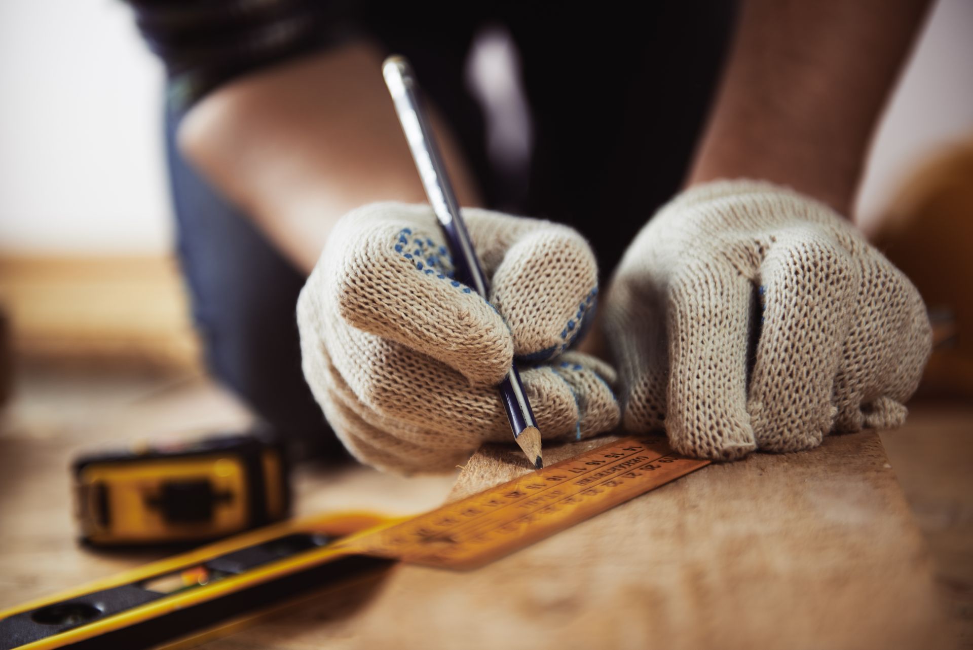 Un artisan prend des mesures avec règle et crayon.