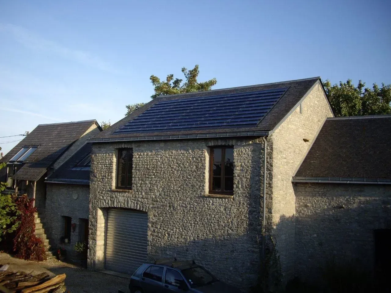 Maison en pierre au toit sombre baignée de soleil.