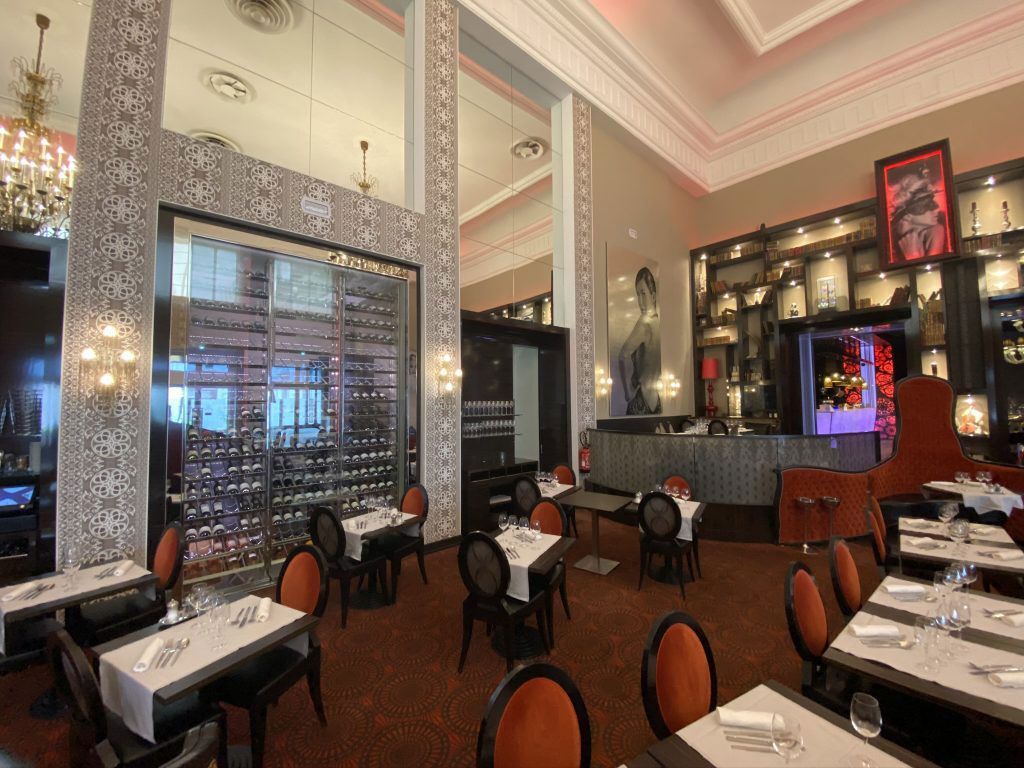 Salle du restaurant avec vue sur la cave à vin et les bouteilles de vin