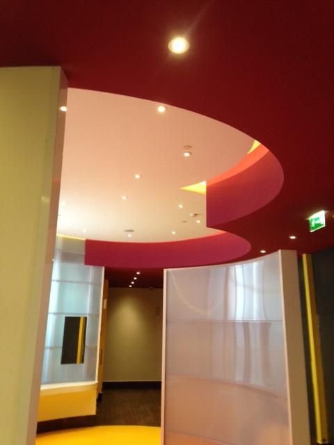 Un plafond incurvé rouge et blanc avec un éclairage encastré.