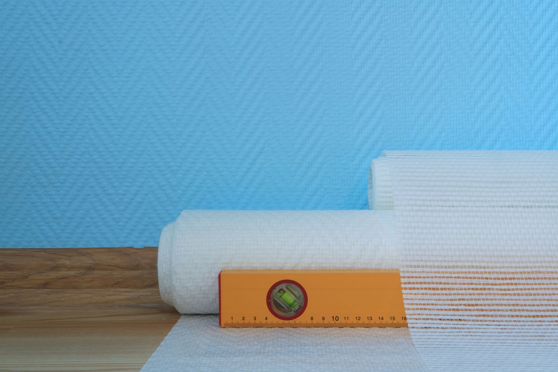 Rouleau de toile de verre posé devant un mur bleu.