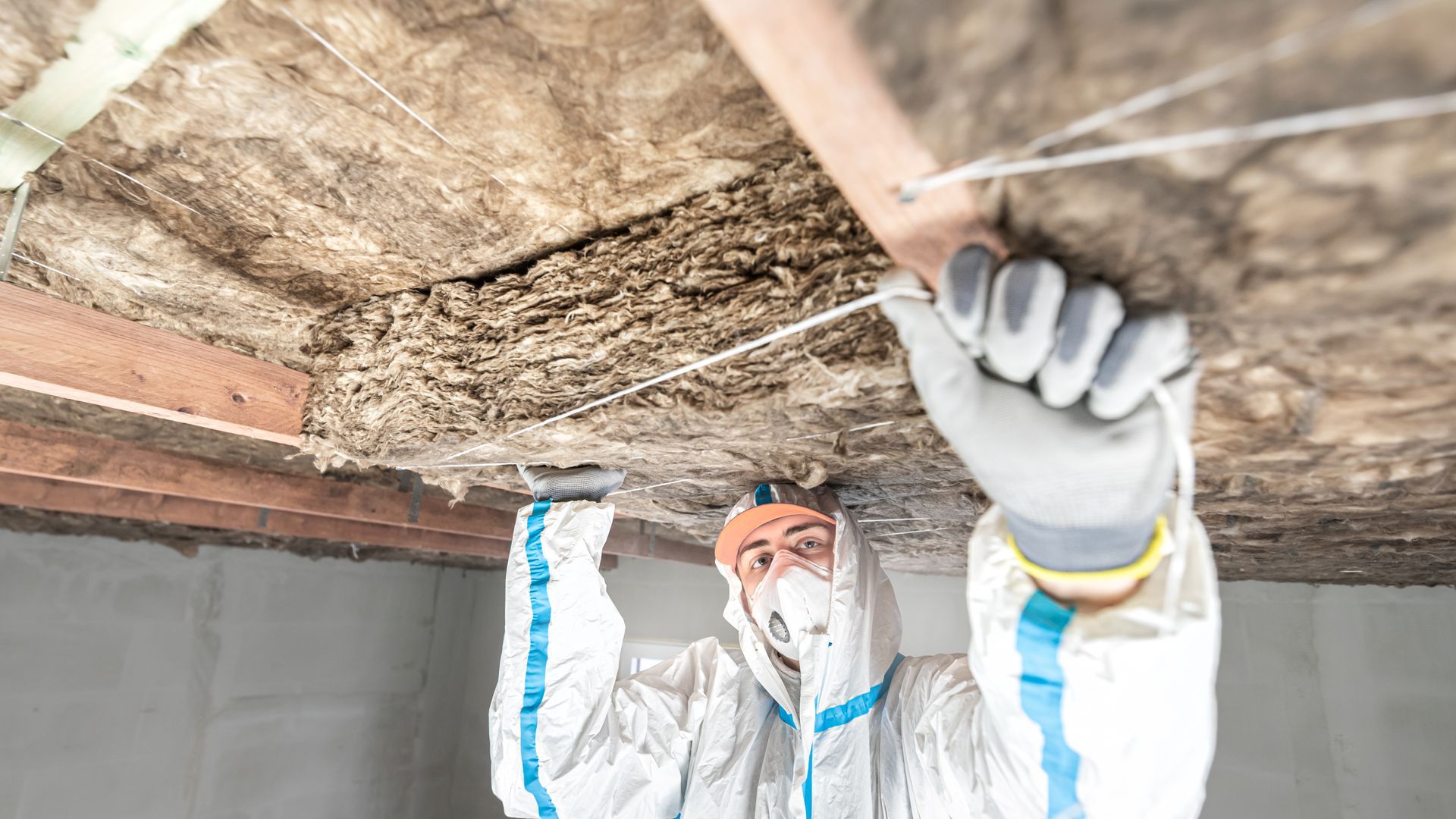 Personne en combinaison de protection inspectant l'isolation du plafond.