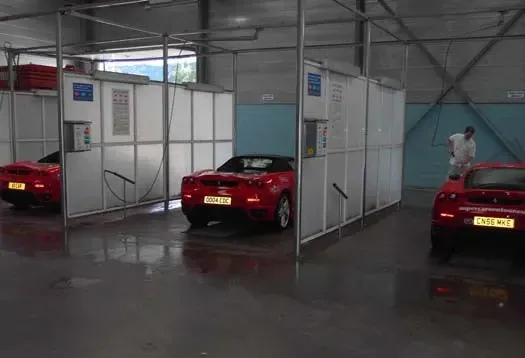 Autos deportivos rojos dentro de una instalación de lavado de automóviles.