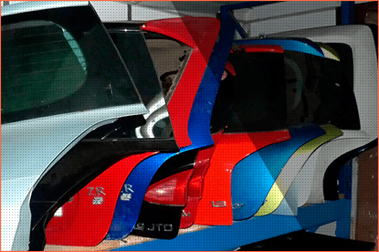 Piezas de automóvil en color rojo, azul y negro, apoyadas contra un vehículo.