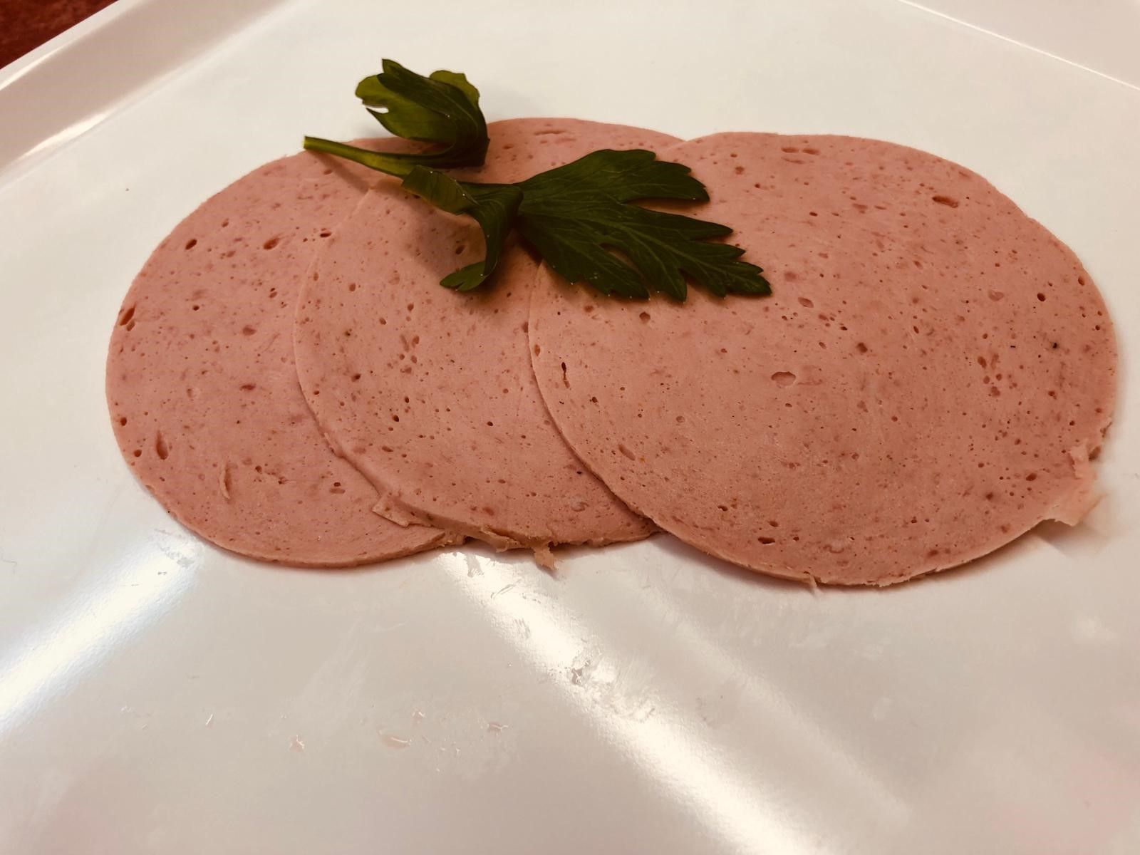 Drei Scheiben Wurst auf einem weißen Teller mit Petersilie