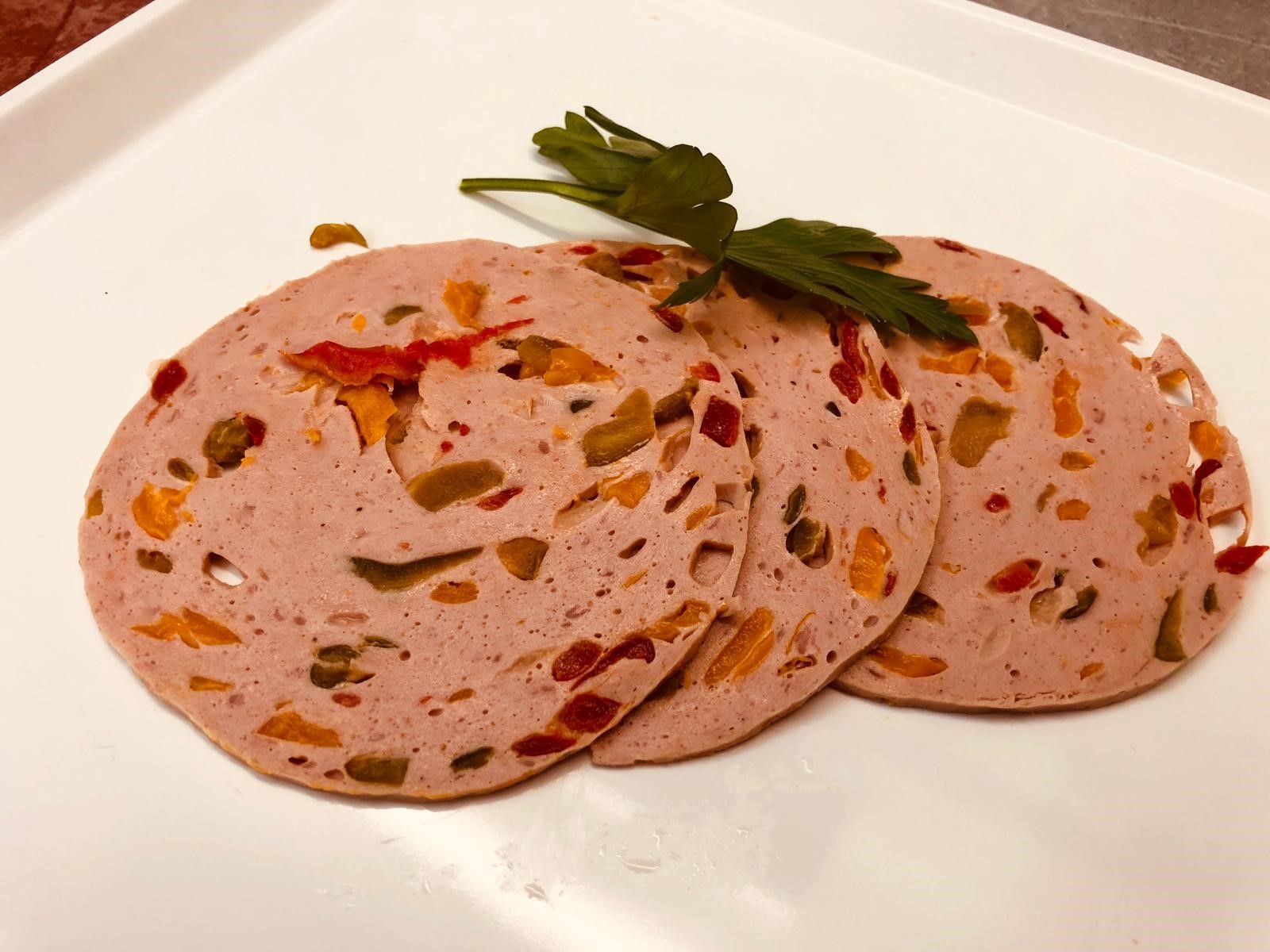 Drei Scheiben Wurst auf einem weißen Teller mit Petersilie