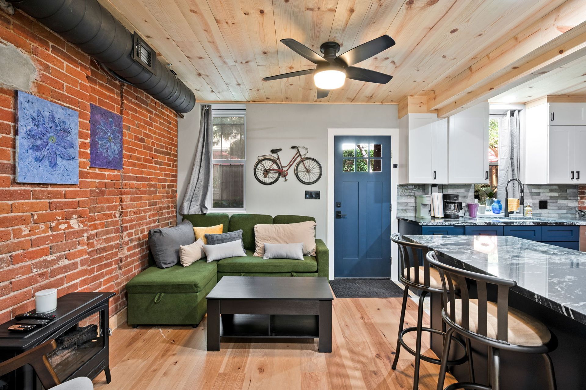 Bedroom with slanted white walls, wooden ceiling, bed, windows, and scenic view.