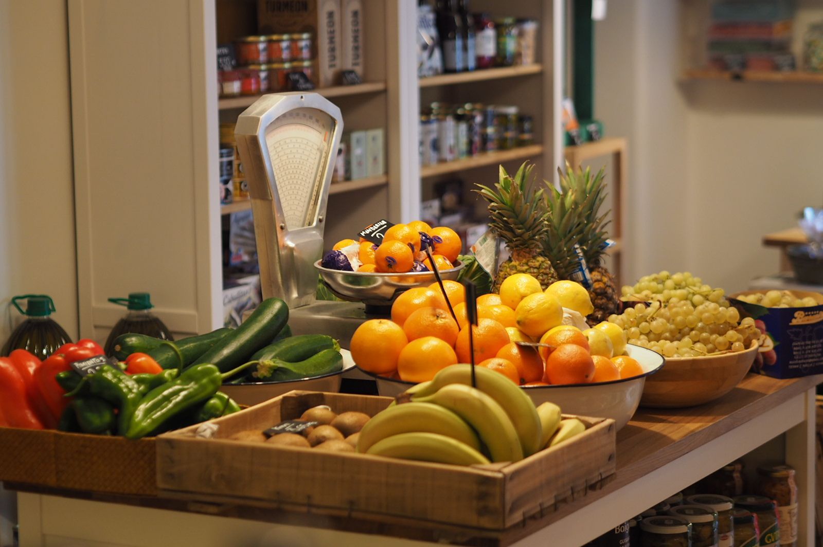 Una mesa llena de frutas y verduras con una balanza al fondo.