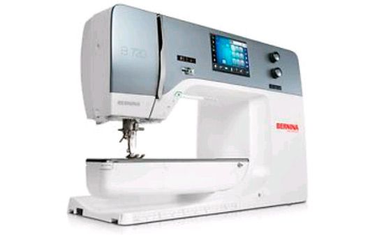 Una máquina de coser blanca está colocada sobre una superficie blanca.