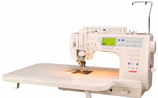 Una máquina de coser blanca está encima de una mesa blanca.