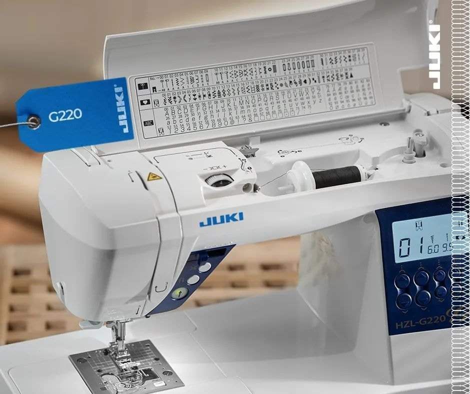 Una máquina de coser Juki blanca y azul está sobre una mesa.