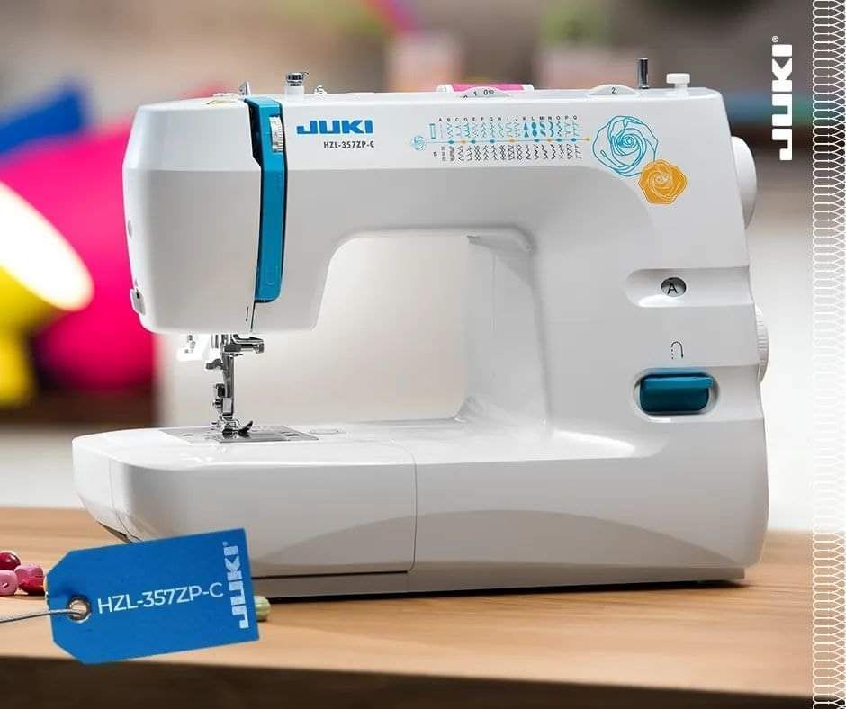 Una máquina de coser Juki blanca está sobre una mesa de madera.