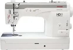Una máquina de coser blanca está sobre una mesa blanca.