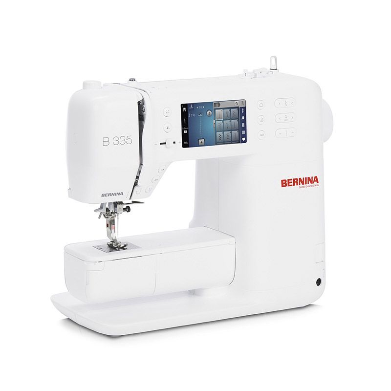 Una máquina de coser blanca está colocada sobre una superficie blanca.