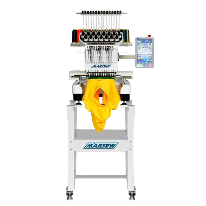 Máquina de bordar automática cosiendo una prenda amarilla sobre un soporte con pantalla de control.