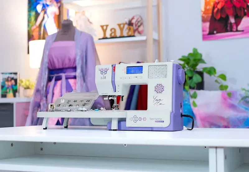 Una máquina de coser blanca está colocada sobre una superficie blanca.