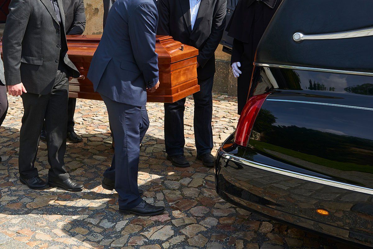 Groupe de personnes qui porte un cercueil pour le mettre dans une voiture