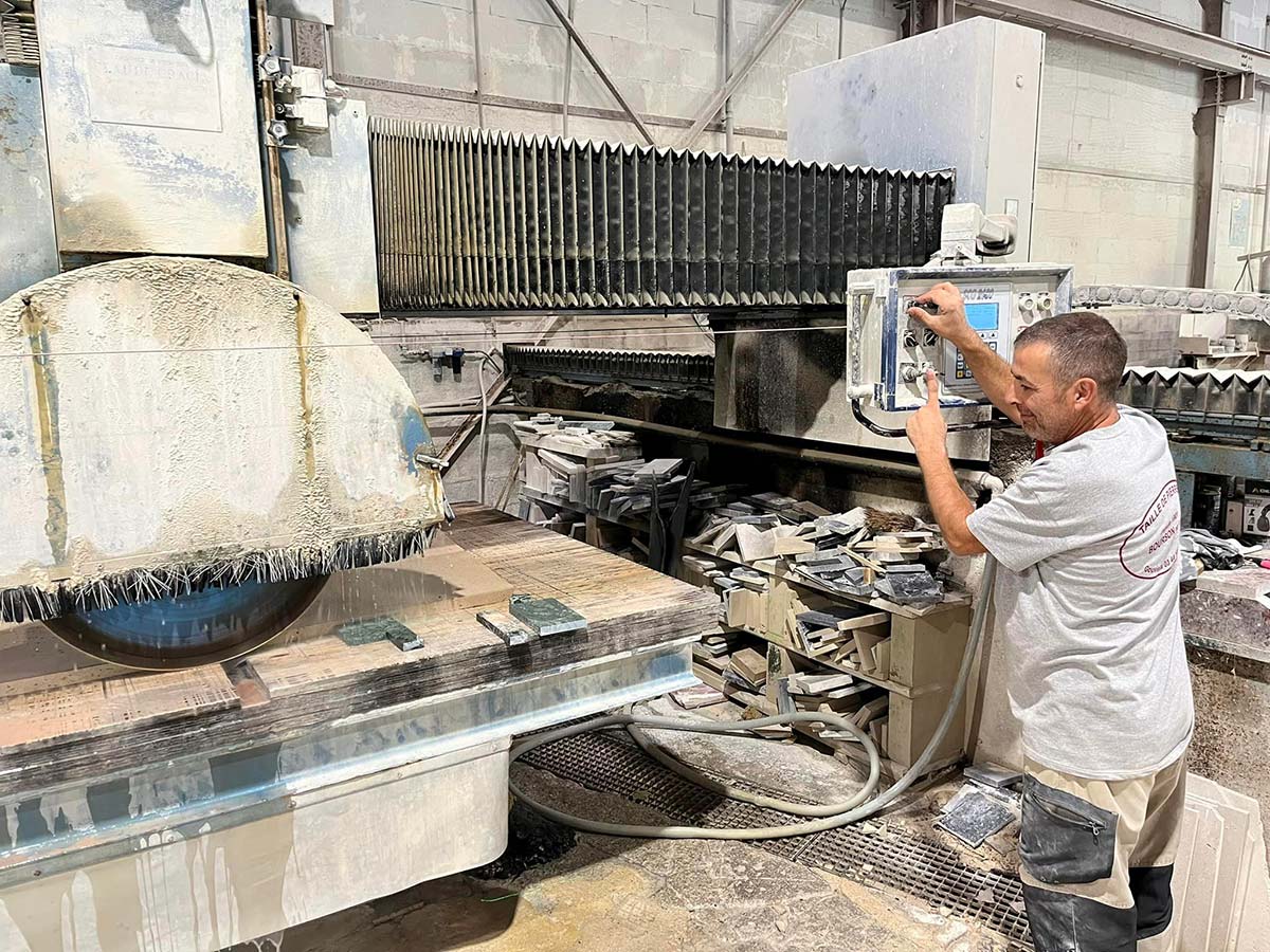 Ouvrier Bourson & Fils qui découpe de la pierre avec une machine industrielle