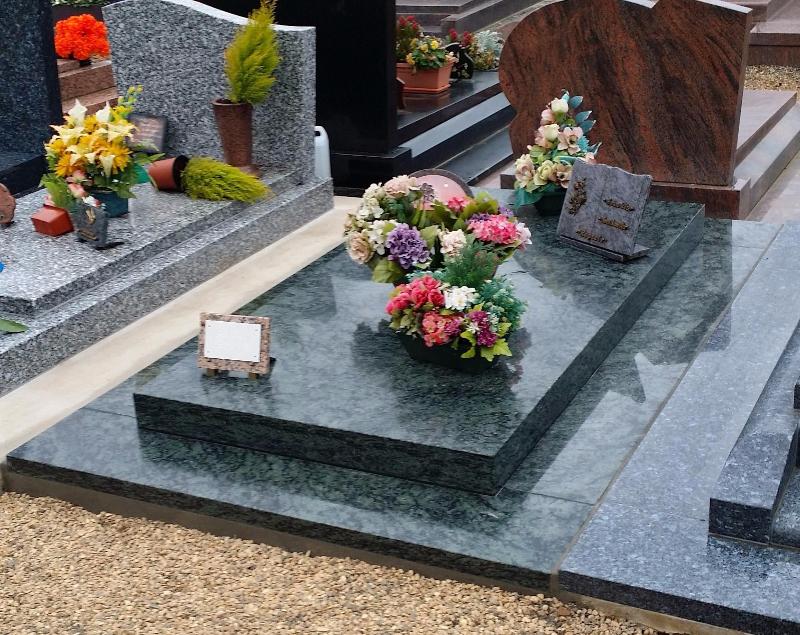 Tombe en granit avec fleurs et plaques posées dessus