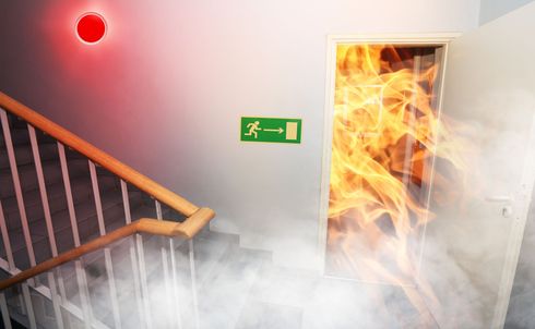 Aus einer Tür in einem Gebäude dringt Feuer.