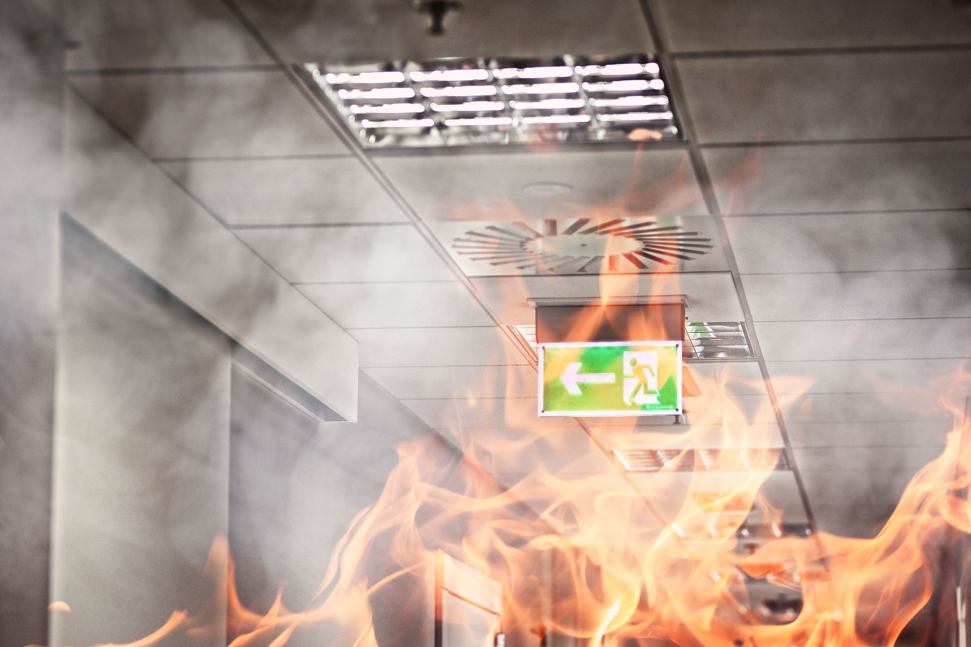 Ein Feuer in einem Bürogebäude, an dessen Decke ein grünes Notausgangsschild hängt.