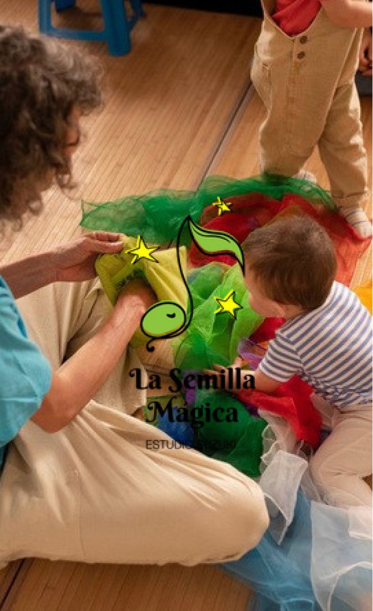 Ariel Sosa y niño pequeño jugando con telas de colores en el suelo.