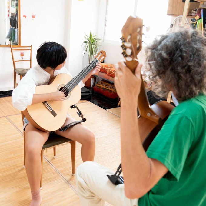 Dos personas están tocando guitarras en una sala de estar.