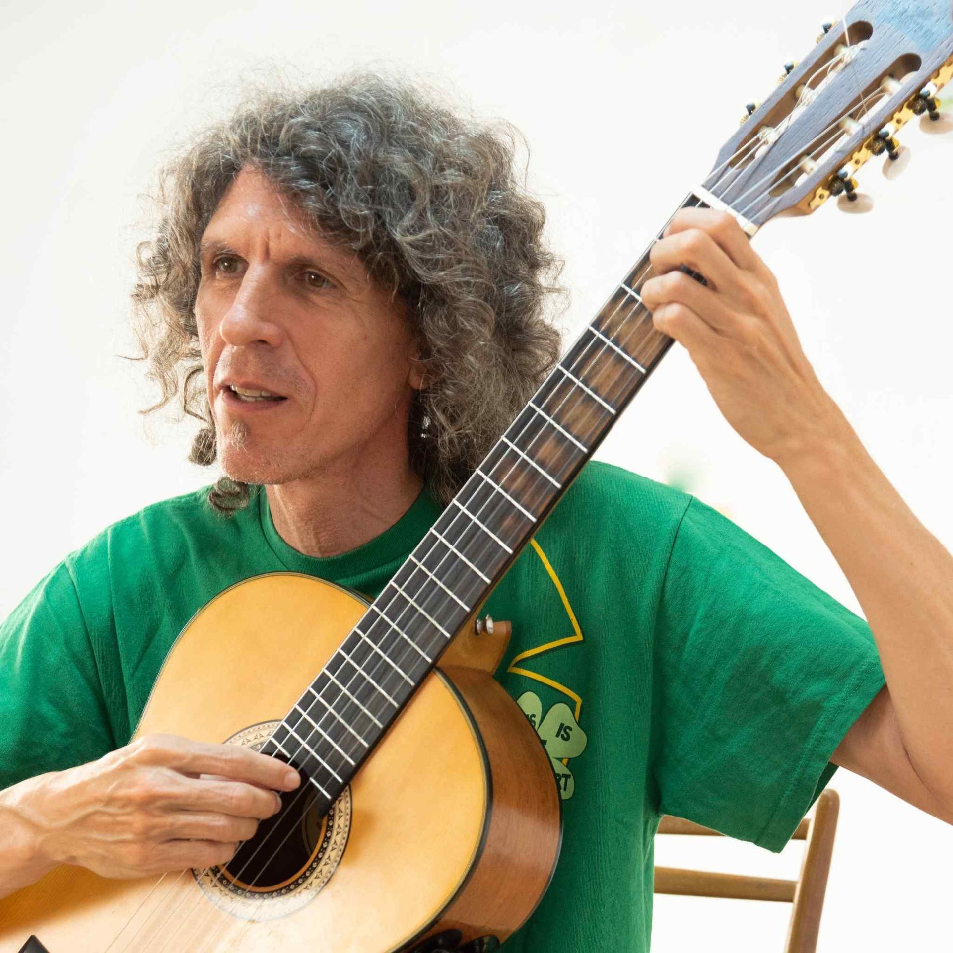 Un hombre con una camisa verde está tocando una guitarra