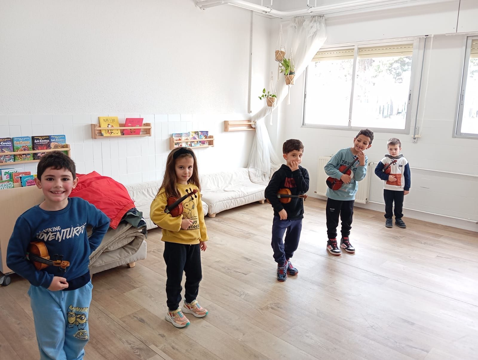 Un grupo de niños está tocando violines en una habitación.