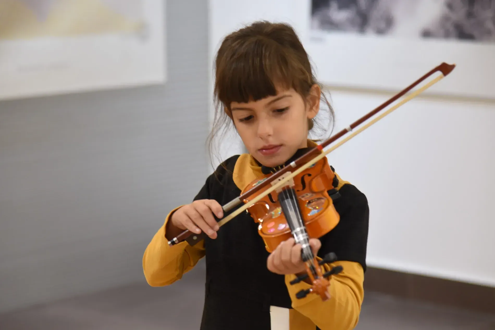 Una niña está tocando un violín en una habitación.