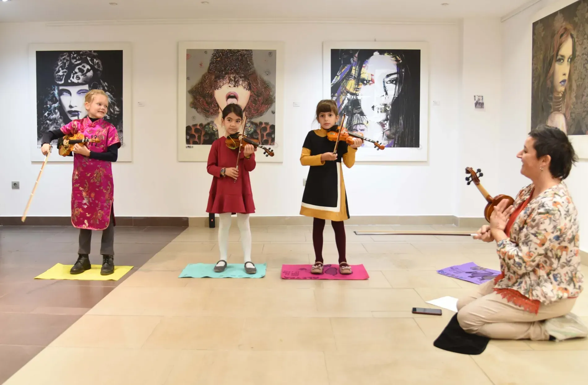 Un grupo de chicas jóvenes tocan violines en una habitación.