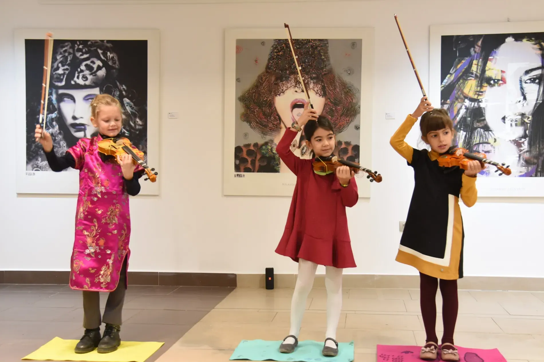 Tres chicas jóvenes están tocando violines en una habitación.