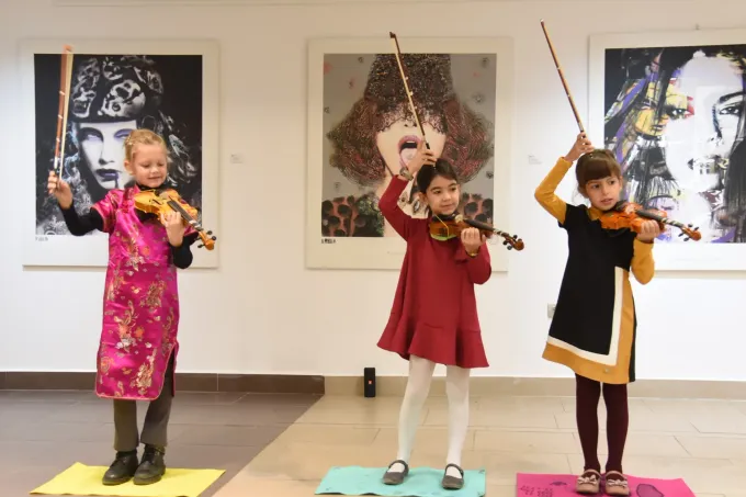 Tres chicas jóvenes están tocando violines en una habitación.